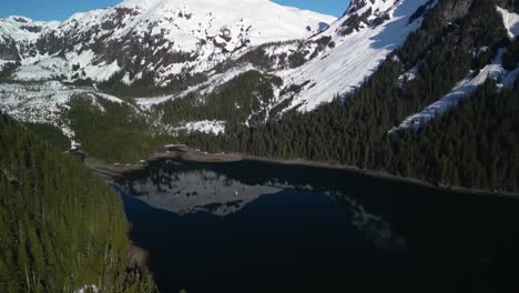 Panorama-Drohnenaufnahme,-Die-Ein-Segelboot-Umkreist,-Das-Inmitten-Der-Schneebedeckten-Berge-Im-Sonnigen-Alaska-Vor-Anker-Liegt