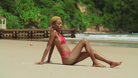 On-the-white-sand-beach-of-the-Caribbean,-a-girl-with-ebony-skin-basks-in-the-sun-in-her-red-bikini