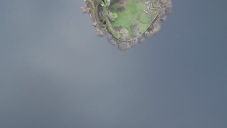 -McDermott-Castle-on-an-island-in-Lough-Key,-County-Roscommon,-Ireland,-surrounded-by-lush-greenery-and-water,-seen-from-above