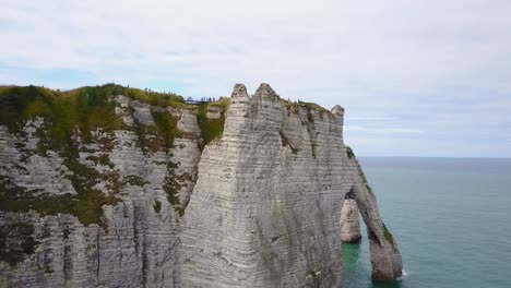 Flying-upward-looking-over-the-arch-of-Etretat-in-Normandy,-France