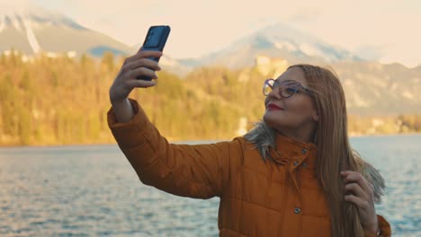4K-video-of-a-beautiful-young-caucasian-female-taking-a-selfie-photo-at-a-very-famous-touristic-destination-Bled,-Slovenia