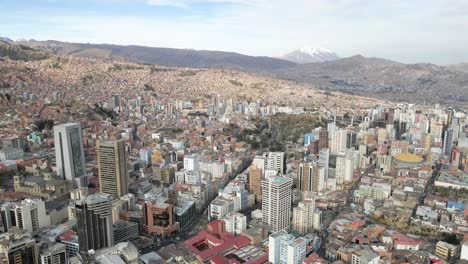 Receding-drone-reveals-La-Paz's-captivating-skyline,-elegantly-framed-by-the-towering-Mt