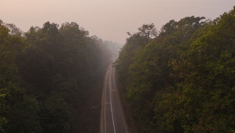 Highway-Drone-shot-in-jungle-with-smoky-foggy-weather-surrounding-trees-in-Eastern-Nepal-Terai-region