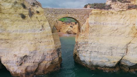 Fly-Away-At-The-Arch-Bridge-At-Paria-dos-Estudantes-In-Lagos,-Algarve,-Portugal