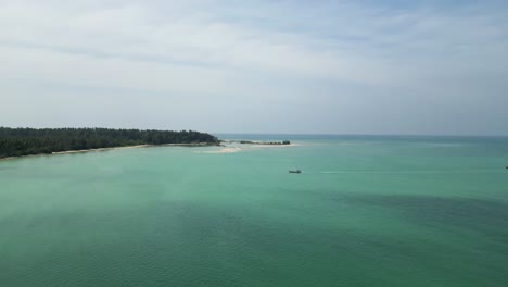 Mango-Bay-in-Ko-Tao-Island-Thailand-with-Long-Tail-boat-approaching-shore,-Aerial-approach-shot