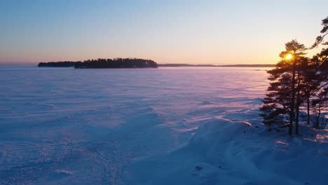 Aerial-view-circling-over-snowy-sea-ice,-winter-sunset-in-the-Finnish-archipelago