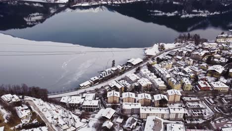 Frozen-lake-and-townscape-of-Zell-Am-See,-Austrian-winter-town,-aerial-sideways