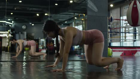 Asiatische-Frau-Macht-Übungen-Im-Indoor-Fitnessstudio-Mit-Spiegel,-Fitness-Mädchen-In-Sportkleidung,-Das-Muskeln-Dehnt