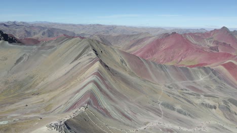 Vuelo-Hacia-Atrás-Captura-La-Montaña-Arcoíris-De-Perú-En-Un-Espectáculo-De-Drones-Con-El-Valle-Rojo-De-Fondo