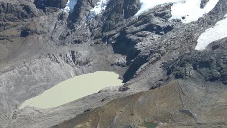 Drone-tilt-up-unveils-Laguna-a-Glaciar-de-Inca,-showcasing-scenic-beauty