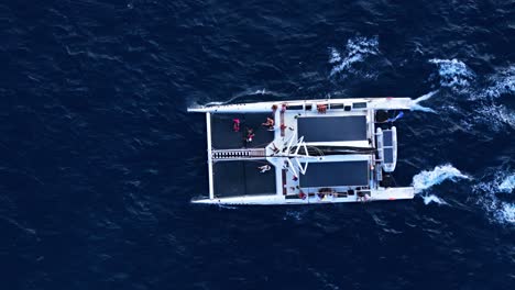 Aerial-top-down-tracking-follows-Catamaran-mast-in-open-ocean-deep-blue-water