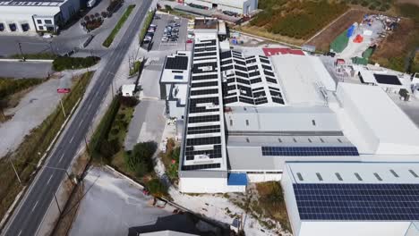 Clean-energy-facility-complex-roof-packed-with-solar-panels,-aerial-panoramic,-backward-dolly-out