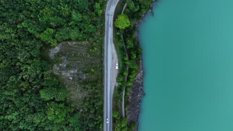 Panoramic-road-between-green-forest-and-banks-of-lake-with-turquoise-and-calm-waters