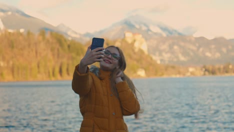 4K-Video-Einer-Schönen-Jungen-Kaukasischen-Frau,-Die-Ein-Selfie-Foto-An-Einem-Sehr-Berühmten-Touristenziel-In-Bled,-Slowenien,-Macht