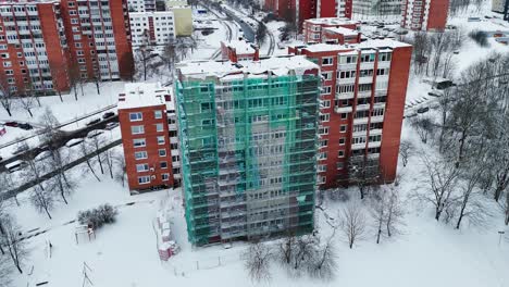 Renovating-a-building-in-winter,-snowy-cityscape-from-drone