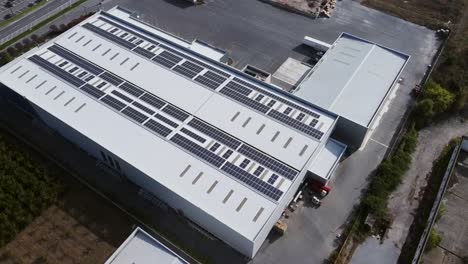Warehouse-white-roof-packed-with-solar-panels,-aerial-bird’s-eye-view