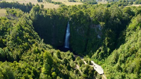 Tilt-up-bird's-eye-view-of-the-Tocoihue-waterfall-on-a-sunny-day-in-a-hidden-environment-in-Chiloé,-Chile