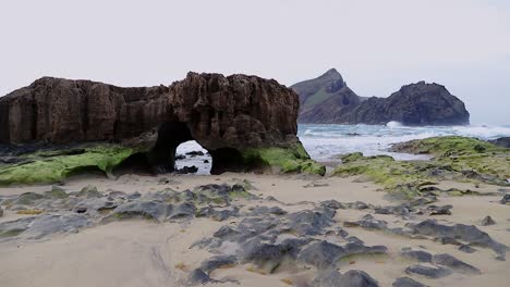 Early-morning-picturesque-sea-view-with-arch-in-islet-beach-sand-rocks-and-waves-at-Porto-Santo-island-in-Portugal-50fps-static-shot