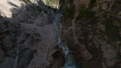 Crazy-drone-racing-freestyle-flight-over-creek-flowing-in-narrow-gorges,-Italian-mountains