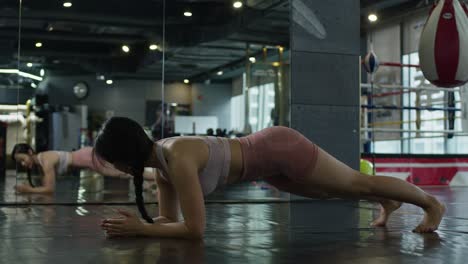 asiatic-young-sexy-female-sporty-woman-performing-exercise-alone-at-gym-looking-at-mirror