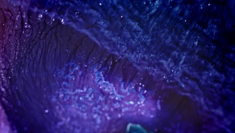 Close-up-of-vibrant-blue-and-purple-ink-diffusing-in-water,-creating-an-abstract-fluid-art-scene
