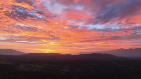 Flug-Bei-Sonnenuntergang-In-Einem-Tal,-Der-In-Einer-Leichten-Rechtskurve-Die-Berge-Und-Wälder-Und-Einen-Spektakulären-Himmel-Mit-Einer-Unglaublichen-Farbpalette-Blau,-Rot,-Gelb,-Orange-In-Avila,-Spanien,-Sichtbar-Macht