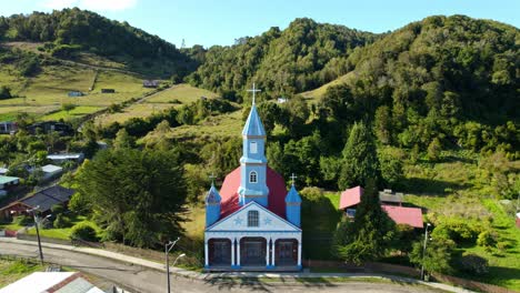 Vista-Aérea-Inclinada-Hacia-La-Iglesia-De-Tenaún-En-La-Soleada-Chiloé,-Chile