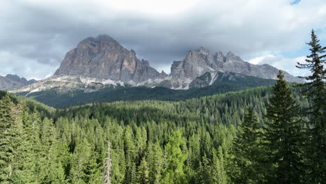 Dolomites-alpine-woodland-push-in-slowly-flying-across-treetops-towards-epic-Italian-mountain-range