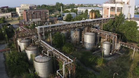 Aerial-shot-of-rusty-factory-containers-and-pipelines-in-abandoned-industrial-area