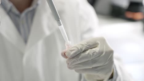Closeup-shot-of-scientist-hands-in-white-gloves-getting-sample-using-absorption-pipette