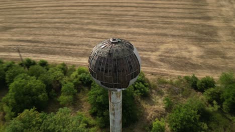 Old-abandoned-destroyed-water-tower,-aerial-orbiting-shot,-summer,-Europe