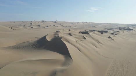 Drone-gracefully-advances,-capturing-the-beauty-of-the-desert-dunes-near-Huacachina