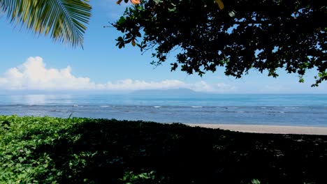 A-glimpse-of-popular-tourism-destination-of-Atauro-Island-through-trees-on-sandy-beach-in-capital-city-of-Dili,-Timor-Leste,-Southeast-Asia