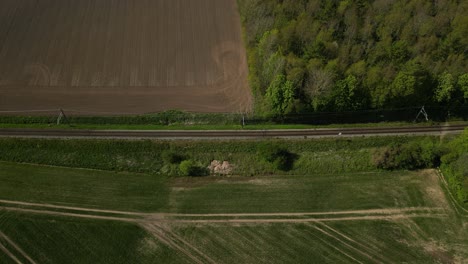 Drone-footage-of-a-train-passing-through-countryside-with-fields-on-either-side-of-the-tracks