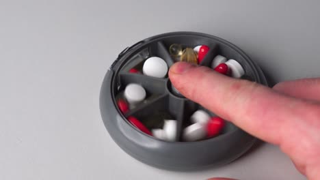 Person-use-finger-to-push-plastic-vitamin-pill-container-button,-change-sections