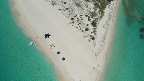 A-pristine-beach-in-los-roques,-venezuela-with-clear-waters-and-a-boat-anchored,-sunny-day,-aerial-view