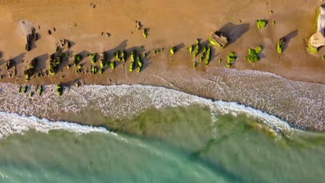 Smooth-slow-motion-golden-beach-sunset-aerial-landscape-of-coastal-erosion-wind-polished-rock-covered-by-green-creamy-algae-the-wave-bubble-foam-on-the-coast-seaside-wonderful-adventure-in-Iran-trip