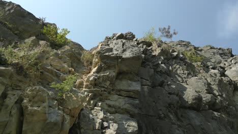Aerial-elevating-low-angle-shot-of-rock-cliff-on-summer-day-in-Europe