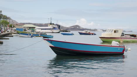 Blue-fishing-boat-sits-high-out-of-water-as-it-is-moored-to-sidewalk-in-the-inlet-of-Carenage-Grenada