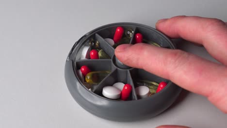 Person-push-plastic-medicine-container-button-and-change-sections,-pills-inside