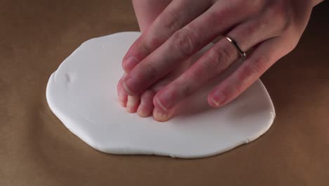 Mother-carefully-push-newborn-baby-foot-to-create-footprint-on-white-clay