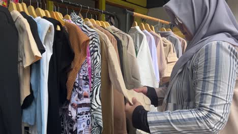 Muslimische-Frau-Wählt-Kleidung-Auf-Einem-Kleiderbügel-Im-Bekleidungsgeschäft-Aus
