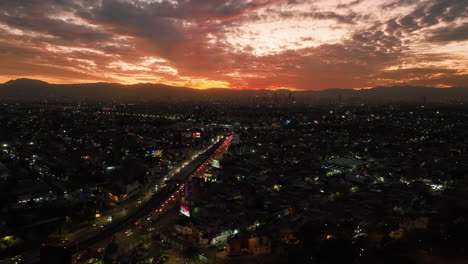 Aerial-tracking-shot-of-a-cloudy-sunset-above-Circuito-Interior-Ave-in-Mexico-City