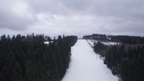 Empty-ski-slope-with-no-snow-next-to-it-due-to-warm-weather,-during-a-stormy-cloudy-day