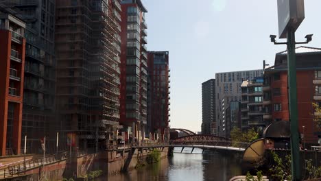 Día-Soleado-En-Manchester-Mostrando-Edificios-Modernos-Junto-A-Un-Río-Tranquilo,-Cielo-Despejado