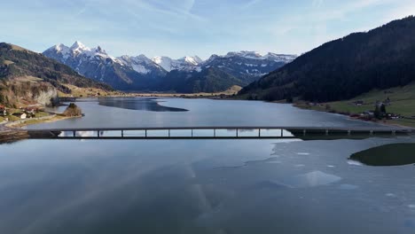 Alpine-landscape-with-Steinbach-Viaduct-over-partially-frozen-Lake-Sihl,-Euthal,-clear-day,-aerial-view
