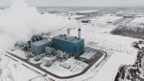 Eine-Industrieanlage-Im-Winter,-Große-Dampfwolken,-Schneebedeckte-Landschaft,-Luftaufnahme