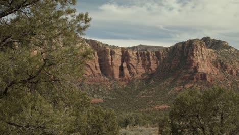 Red-rocks-and-buttes-in-Sedona,-Arizona-with-car-driving-by-with-a-stable-video-shot