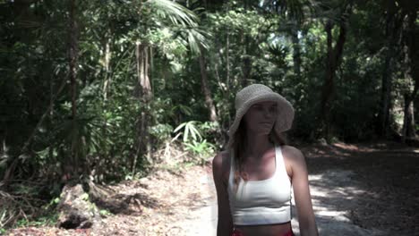 A-Woman-tourist-walking-happilying-a-long-a-jungle-path-inside-Tikal-National-Park,-Guatemala