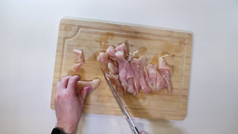 Hands-Cutting-Raw-Chicken-Meat---High-Angle,-Close-Up
